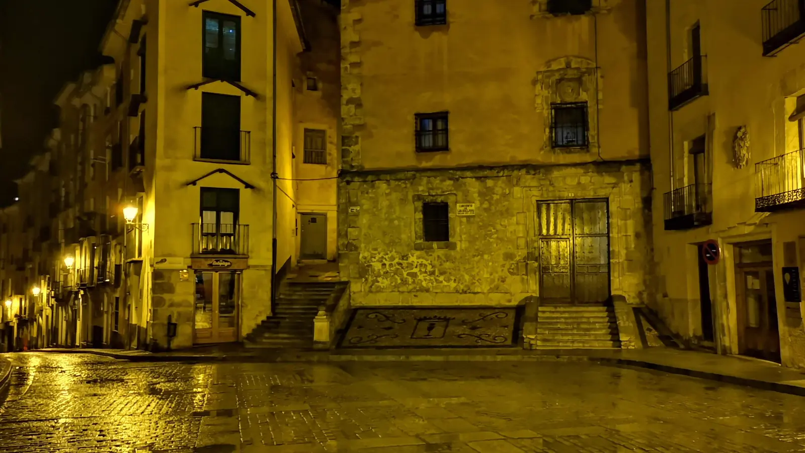 Calles empedradas del casco antiguo de Cuenca de noche, con las farolas reflejadas en el suelo mojado