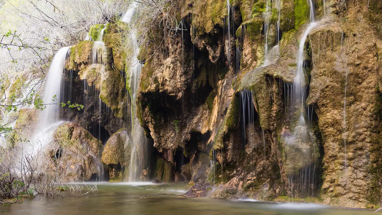 Cascadas del nacimiento del río Cuervo entre roca travertina cubierta de musgo